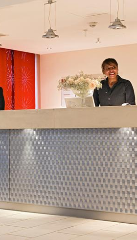 De moderne receptie van het kindvriendelijke Mercure Hotel Duisburg City, waar het personeel klaarstaat om gezinnen te verwelkomen.