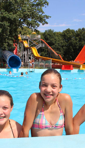 Drie lachende meisjes in bikini poseren in het grote buitenzwembad van Waterspeelpark Splesj bij Molecaten Park Bosbad Hoeven.