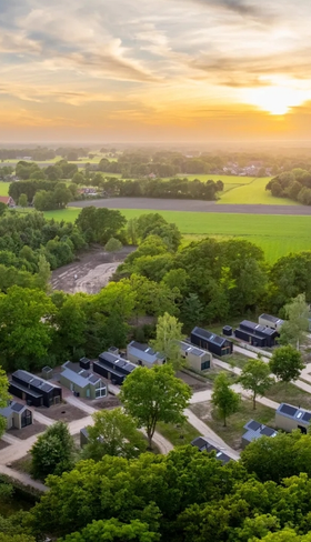 Luchtfoto van vakantiepark Olde Kottink in Overijssel bij zonsondergang, prachtig gelegen in het groene Twentse landschap.