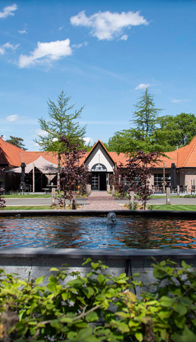 De entree van Resort Veluwe met een karakteristiek gebouw en een waterpartij, gelegen op de Veluwe.