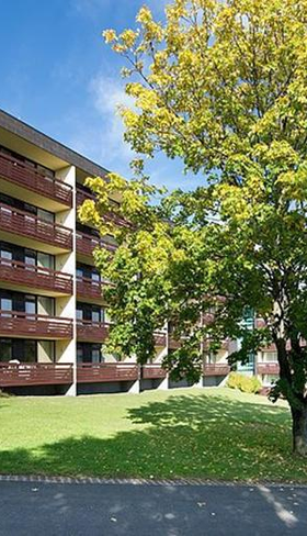 De buitenkant van een van de appartementengebouwen van Rhön Park Aktiv Resort, gelegen in het groene heuvellandschap van Beieren.
