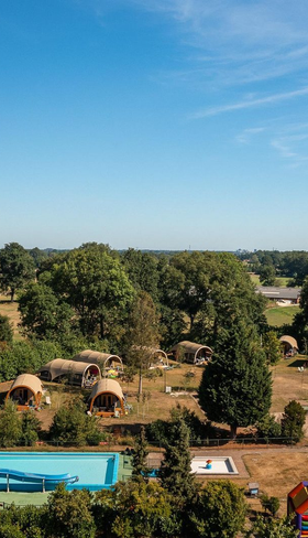Een luchtfoto van Vakantiecentrum 't Schuttenbelt in Twente, met het grote buitenzwembad met waterglijbaan en de lodges in een groene omgeving.