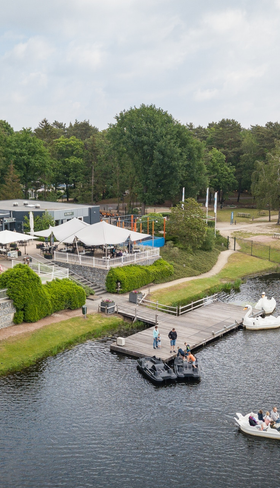 Luchtfoto van Vakantiepark Bospark 't Wolfsven in Noord-Brabant, met een jachthaven aan het recreatiemeer, bootjes en omringende bossen.