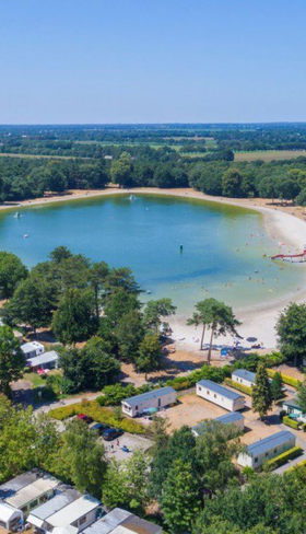 Luchtfoto van Vakantiepark De Bergen in Wanroij, met een grote recreatieplas omgeven door bos en kampeerplaatsen.