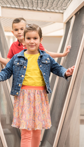 Twee kinderen, een jongen en een meisje, spelen vrolijk op een moderne houten loopbrug bij Vakantiepark De Krim op Texel.