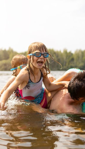 Kinderen spelen en zwemmen vol plezier in het natuurlijke zwemwater van de recreatieplas op Vakantiepark De Strabrechtse Vennen.