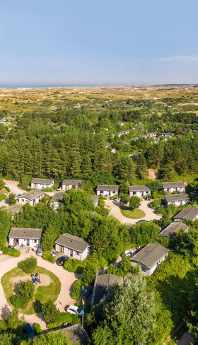 Luchtfoto van Roompot Vakantiepark Egmond aan Zee, met de chalets gelegen in een groene omgeving vlakbij het uitgestrekte duingebied van Noord-Holland.