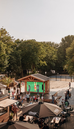 Overzicht van de levendige centrale plaza op Vakantiepark Kijkduin, met zonnige terrassen, horeca en veel gezelligheid in de duinen.