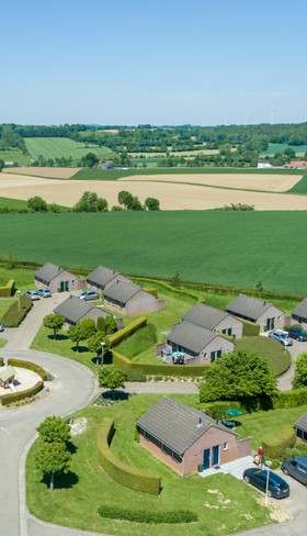 Luchtfoto van de vakantiehuisjes van Vakantiepark Reevallis, gelegen in het glooiende heuvellandschap van Zuid-Limburg.