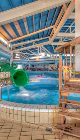 Het subtropisch zwemparadijs van Vakantiepark Weerterbergen met een houten speeltoestel en de waterglijbaan op de achtergrond.