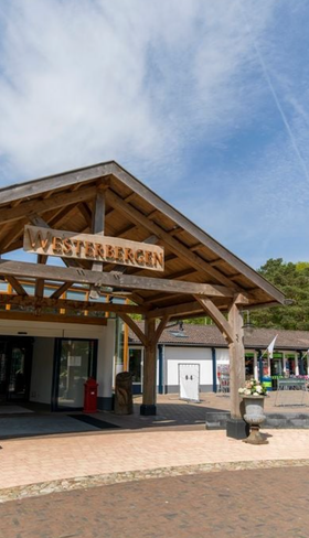 De houten entree van het centrumgebouw (Plaza) van Vakantiepark Westerbergen in Echten, Drenthe op een zonnige dag.