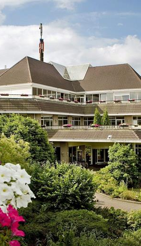 Buitenaanzicht van het kindvriendelijke Van der Valk hotel in Gladbeck, Noordrijn-Westfalen, omgeven door groene tuinen en kleurrijke bloemen.