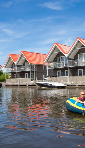 De karakteristieke waterwoningen van Waterpark Terherne in Friesland, gelegen aan het water met verschillende bootjes en Friese skûtsjes.