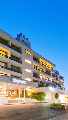 De moderne buitenkant van het verlichte Dorint Hotel & Sportresort Arnsberg-Sauerland in de avond.