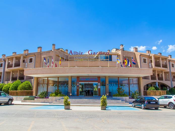 De hoofdingang van het Albir Garden Resort & Aquapark, een zandkleurig gebouw onder een strakblauwe Spaanse hemel.