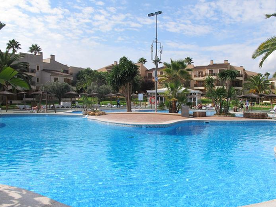 Het grote, rustige lagune-zwembad van Albir Garden Resort, omringd door palmbomen en de appartementen van het resort.