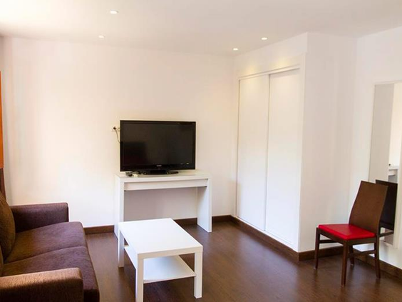 De eenvoudige en functionele woonkamer in een appartement van Albir Garden Resort, met een bank, tv en een salontafel.