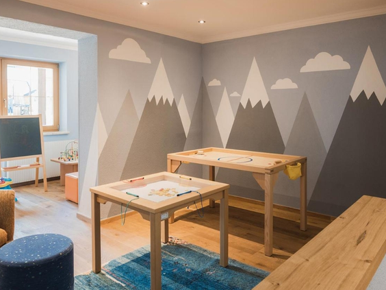 Speelkamer voor kinderen met speels behang en tafels met spelletjes