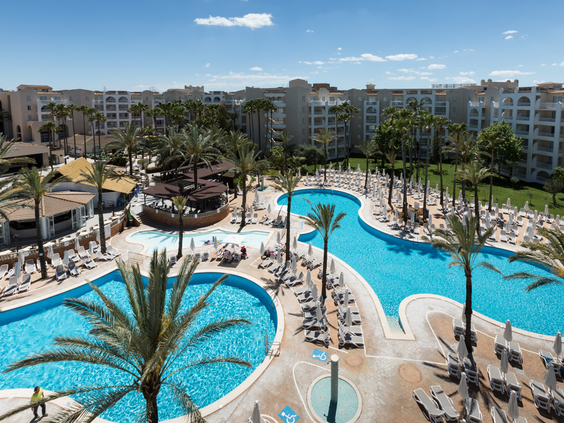 Een overzichtsfoto van het grote zwembadcomplex van Aparthotel Protur Safari Park op Mallorca, met lagune-stijl baden en palmbomen.