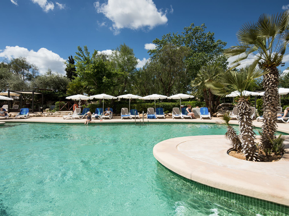 Het prachtige lagune-stijl zwembad van Protur Safari Park, met helderblauw water en ligbedjes met parasols aan de rand.