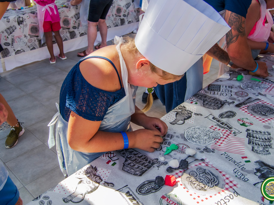 Een kind met een koksmuts op, druk bezig met een creatieve workshop van de kidsclub bij Protur Safari Park.