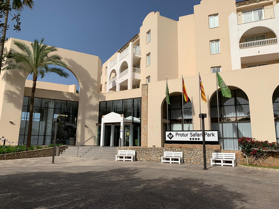 De chique hoofdingang van Aparthotel Protur Safari Park op Mallorca, met een grote glazen entree en witte bankjes.