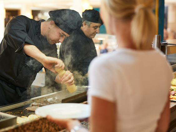 Een kok die vers eten bereidt voor een gast bij de showcooking-sectie van het buffetrestaurant in Protur Safari Park.