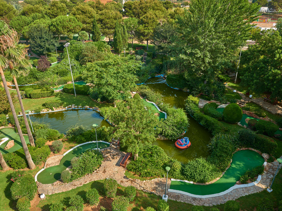 Luchtfoto van de uitgebreide en groene minigolfbaan van Protur Safari Park, gelegen tussen de bomen en met waterpartijen.