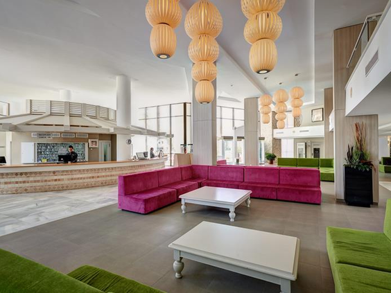 De moderne en kleurrijke lobby van Protur Safari Park, met grote roze en groene loungebanken.