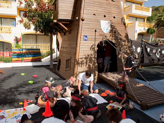 Een groep kinderen is druk aan het knutselen op de grond tijdens een activiteit van de kinderclub bij Royal Son Bou, begeleid door het animatieteam.