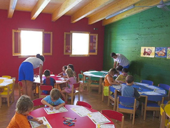Kinderen zitten aan tafeltjes te kleuren en knutselen onder begeleiding van het animatieteam in de kidsclub van Royal Son Bou.