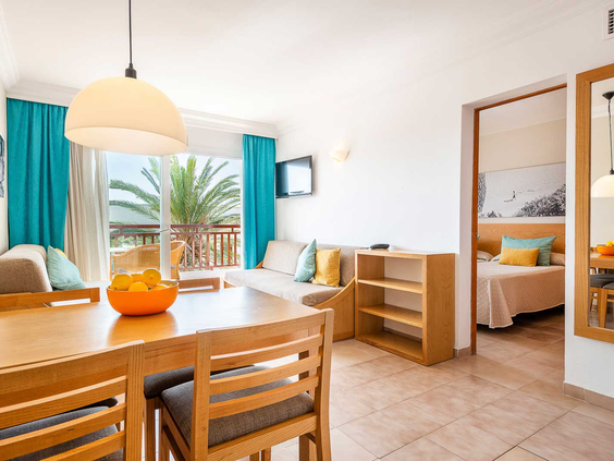 Het interieur van een ruim standaard appartement in Esmeralda Park op Mallorca, met een woonkamer, eethoek en aparte slaapkamer.