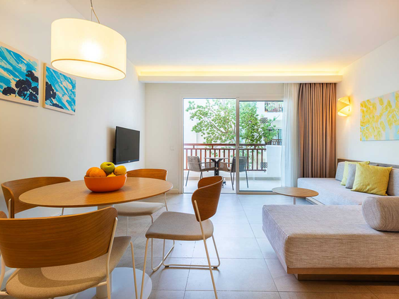 De lichte woonkamer van een appartement bij Esmeralda Park op Mallorca, met een eethoek, bank en deur naar het balkon.