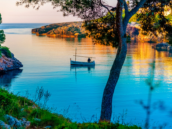 Een idyllische baai bij Cala d'Or op Mallorca tijdens een sfeervolle, gouden zonsondergang.
