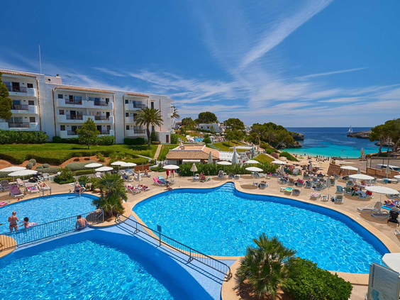 Overzicht van het prachtige resort Appartementen Esmeralda Park, met het grote zwembad direct aan het zandstrand en de baai Cala Esmeralda.
