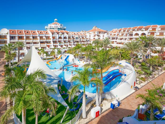 Overzicht van het zwembadcomplex met een klein waterpark en kronkelende glijbanen bij de appartementen van Parque Santiago III.