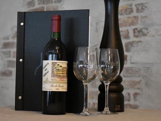 Een fles rode wijn met twee glazen en een menukaart in het restaurant van Hotel Atlanta voor een gastvrij en stijlvol verblijf