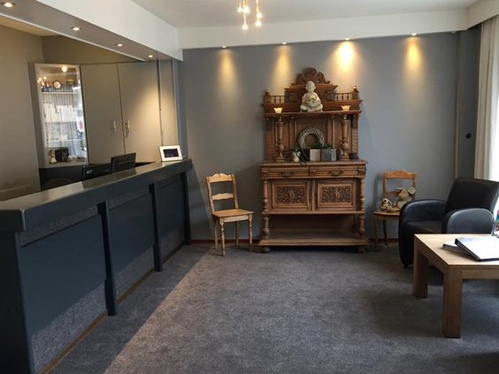 De receptie van Hotel Atlanta waar een modern grijs interieur wordt gecombineerd met een antiek houten dressoir
