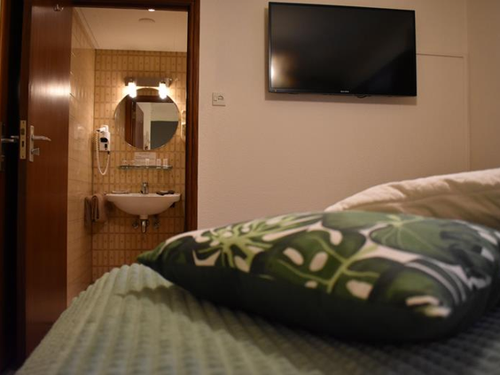 Hotelkamer in Hotel Atlanta met een groen bed en een open deur naar de en suite badkamer