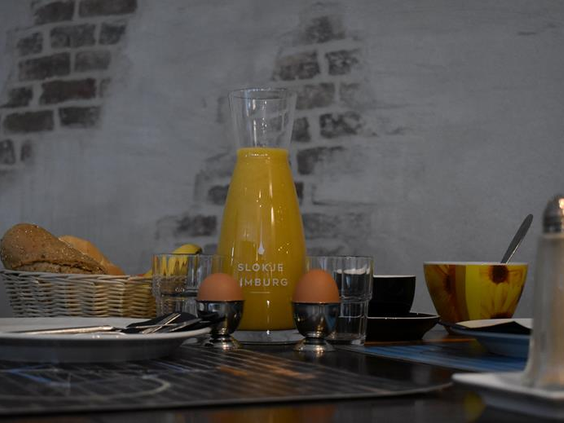 Uitgebreid ontbijt in Hotel Atlanta met een karaf verse jus d'orange gekookte eieren en broodjes tegen een sfeervolle bakstenen muur
