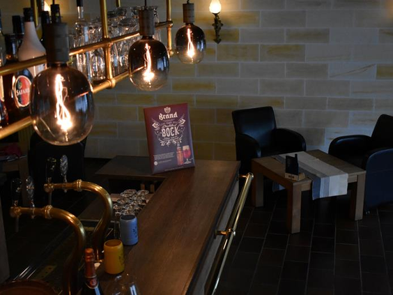 Zithoek in de bar van Hotel Atlanta met industriële verlichting en zwarte leren stoelen tegen een lichte bakstenen muur