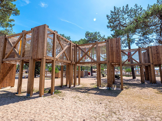 Groot avontuurlijk houten klimfort in een zandspeeltuin, gelegen in het dennenbos van de kindvriendelijke camping Atlantic Club Montalivet.