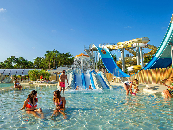 Kinderen en volwassenen spelen in het grote zwembad van het waterpark met diverse spectaculaire glijbanen op de kindvriendelijke camping Atlantic Club Montalivet.