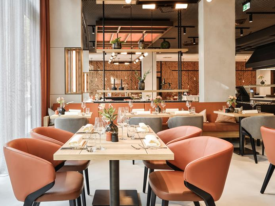 Het sfeervolle en modern ingerichte restaurant van het ATLANTIC Hotel Münster, met gedekte tafels voor een familiediner.
