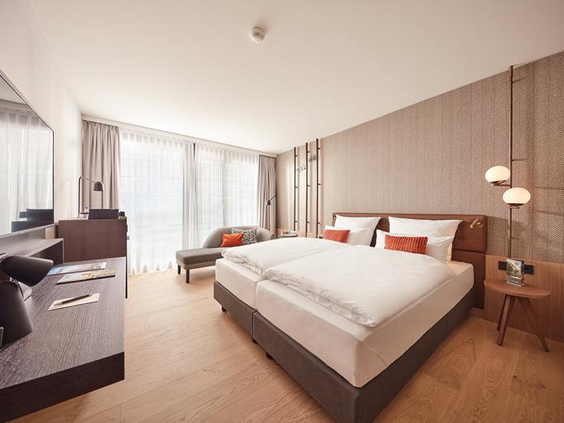 Een ruime en luxe hotelkamer in het ATLANTIC Hotel Münster, met een comfortabel groot bed voor het hele gezin.