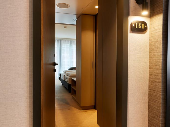Een gang in het ATLANTIC Hotel Münster die leidt naar een van de moderne en comfortabele familiekamers.