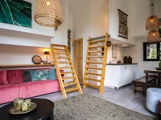 Het hippe en duurzame interieur van een Wikkelhouse op Bad Hoophuizen, met een gezellige zithoek en trappetjes naar de slaapvides.