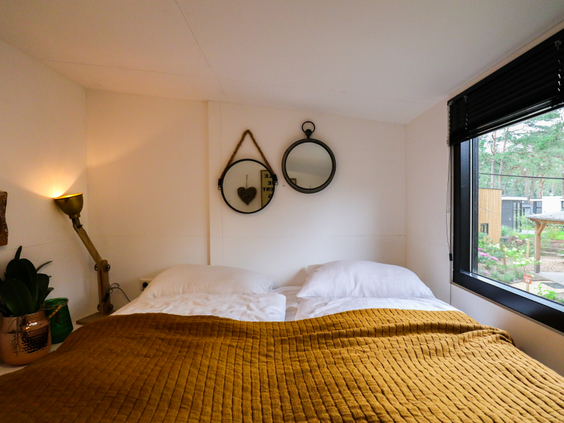 Een sfeervol ingerichte slaapkamer met een comfortabel opgemaakt tweepersoonsbed in een vakantiehuisje op Bad Hoophuizen.
