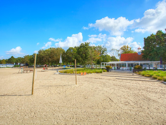 Het ruime zandstrand van Bad Hoophuizen met een beachvolleybalnet, direct gelegen aan het Veluwemeer.