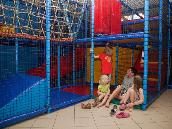 Kinderen spelen in de kleurrijke indoor binnenspeeltuin van Vakantiepark Bad Hoophuizen, met klimnetten en zachte speelelementen.